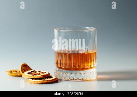 Whisky oder Rum in einem Kristallglas, garniert mit getrockneten Orangenscheiben. Kopierraum. Stockfoto
