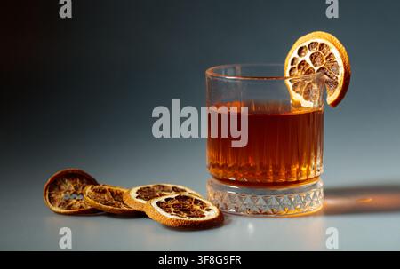 Erfrischender Rum-Cocktail, garniert mit getrockneten Orangenscheiben in einem Kristallglas. Kopierraum. Stockfoto