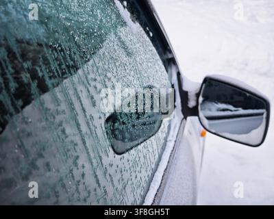 Eiskristalle auf einer Autoscheibe im Winter. Kaltes Wetter, gefrorenes Glas und Transportkonzept Stockfoto