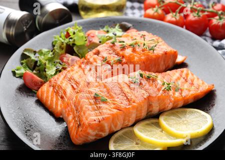 Stücke gegrillten Lachses, serviert mit Salat auf dem Tisch, Nahaufnahme Stockfoto