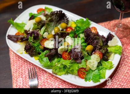 Gemischter Salat aus Gurke, Salat, Tomaten und Oliven in Nahaufnahme Stockfoto
