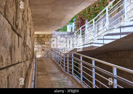 Moderner Steinarchitektur-Pfad mit weißen Geländern und blühenden Blumen Stockfoto
