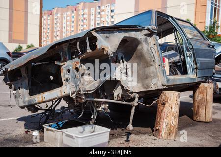 Demontiertes Autochassis mit rostigem Metall, beschädigten Fahrzeugteilen, Autoreparatur und Schrott. Stockfoto