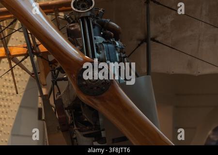Eine Nahaufnahme zeigt eine polierte Holzpropeller, der am freiliegenden Motor eines Vintage-Flugzeugs in Innenräumen montiert ist. Stockfoto