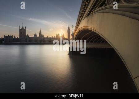 Blick auf das Westminster-Palast und Big Ben bei Sonnenuntergang von unter der Westminster-Brücke aus, mit der Themse im Vordergrund in London, England, Uni Stockfoto
