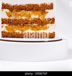 Ein kunstvoll gestalteter Schichttorte zeigt reiche braune Schichten, gefüllt mit süßer Apfelcreme und cremiger Glasur. Sie wird auf einem einfachen weißen Tortenständer präsentiert, der ihre Textur hervorhebt. Stockfoto