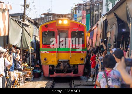 Maeklong, Thailand - Dezember, 19 2023: Zug bewegt sich langsam durch den geschäftigen Maeklong-Eisenbahnmarkt, während Touristen die einzigartige Szene festhalten Stockfoto