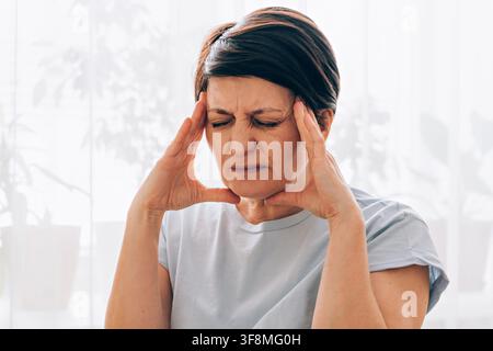 Ältere kaukasische Frau, die zu Hause Kopfschmerzen oder Stress verspürt Stockfoto
