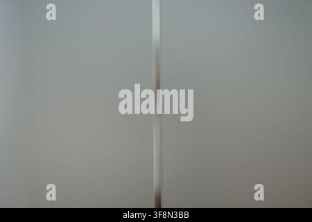 Minimalistische Milchglasscheibe mit einem schlanken Metallrahmen vertikal. Stockfoto
