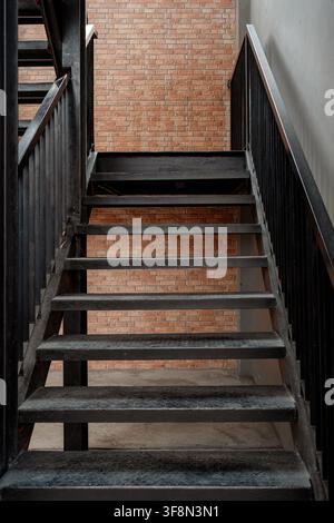Metalltreppe in Schwarz vor einer roten Ziegelwand in einem Industriegebäude. Stockfoto