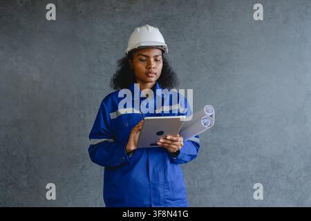 Porträt eines Ingenieurs mit Sicherheitshelm und Uniform vor grauem Hintergrund, der konzentriert und professionell wirkt und repräsentiert. Stockfoto