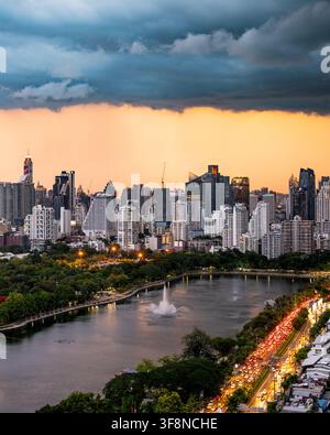 Bangkok, Thailand - 20. Juni 2024: Blick auf die Skyline von Bangkok bei Sonnenuntergang mit dramatischen Gewitterwolken über dem Benjakitti Park, mit dichter urbaner Architektur Stockfoto
