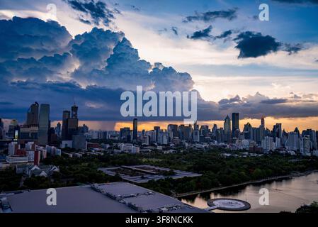 Bangkok, Thailand - 20. Juni 2024: Blick auf die Skyline von Bangkok mit modernen Wolkenkratzern und dramatischen Gewitterwolken bei Sonnenuntergang über dem See in Benjak Stockfoto