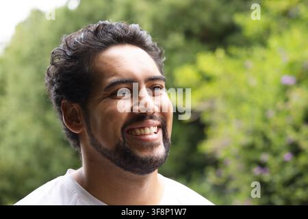 Mittelalter Afrikaner lächelt und schaut leicht nach rechts im Garten, trägt ein weißes Rundhalsshirt Stockfoto