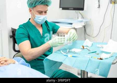 Gesundheitsarbeiter, der einen Kittel und eine Maske trägt, reinigt Instrumente auf einem Wagen in einem Krankenhaus oder einer Klinik Stockfoto