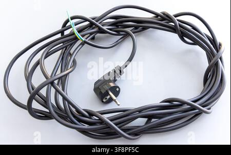 Ein aufgerolltes schwarzes Stromkabel verfügt über einen europäischen Stecker und abgeisolte Drähte Stockfoto