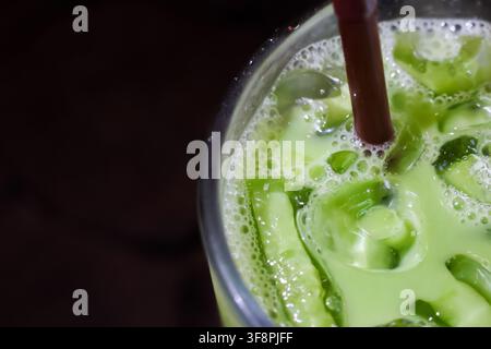 Ein eisgekühlter Matcha-Latte mit Eiswürfeln und Strohhalm, cremiges grünes Teegetränk mit Blasen und erfrischender Textur, Nahaufnahme von Lebensmittelgetränkefotografie Stockfoto