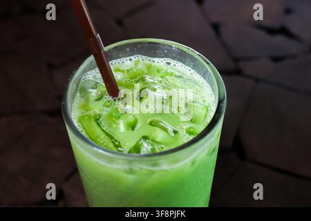 Ein eisiges grünes Matcha-Getränk mit Strohhalm und sprudelndem Schaum in klarem Glas, erfrischendes kaltes Getränk über Eis serviert für den Sommergenuss Stockfoto