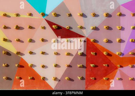 Eine farbenfrohe Wand mit mehreren Klettergriffen für das vertikale Training Stockfoto