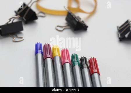 Bunte Filzstifte mit Bindeklammern und Gummiband auf weißem Hintergrund Stockfoto