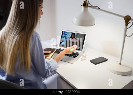 Frau am Laptop, die ein Online-Videogespräch mit einer traurigen jungen Frau führt, psychologische Unterstützung und Ferntherapie Stockfoto