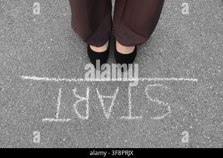 Person, die an einer Kreide-Startlinie auf Asphalt steht, Konzept für neue Anfänge und Karriereweg, Blick von oben Stockfoto