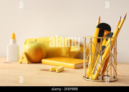 Schulbedarf und Schreibwaren in Gelb und Gold auf einem Holzschreibtisch, zurück zur Schule Stockfoto