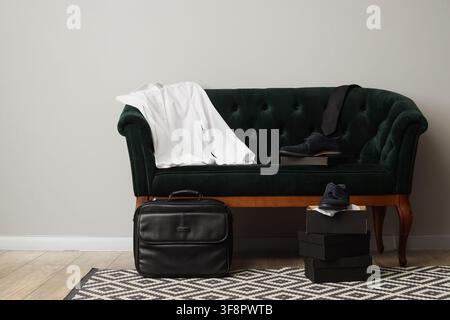 Herrenformkleidung mit weißem Hemd, schwarzer Krawatte und blauen Wildlederschuhen auf einem grünen Samtsofa, Geschäftskleidung Stockfoto