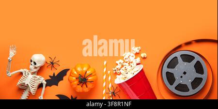 Halloween-Filmnacht-Flachlage mit Skelett, Kürbis, Popcorn und Filmrolle auf orangefarbenem Hintergrund Stockfoto