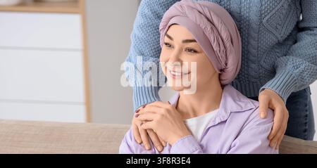 Lächelnde Frau mit Krebs, die einen Kopftuch trägt, Unterstützung von einem Freund erhält, Gesundheit und Wohlbefinden Stockfoto