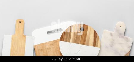Sortiment an modernen Küchen Schneidebrettern aus Holz und Marmor auf einem hellgrauen Hintergrund, die Kollektion umfasst verschiedene Formen und Designs, Stockfoto