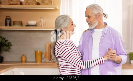 Glückliches älteres kaukasisches Paar tanzt zusammen in der Küche, Senior-Lebensstil-Konzept Stockfoto
