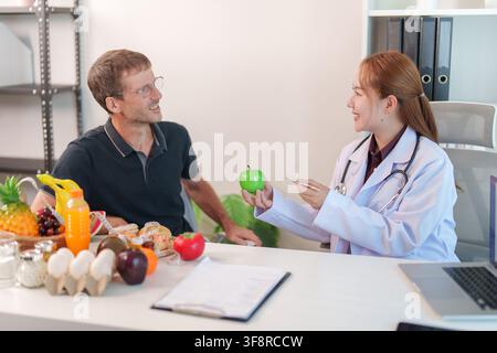 Ernährungsberaterin gibt einem männlichen Patienten mit grüner Apfel in ihrem Büro Ernährungsratschläge Stockfoto