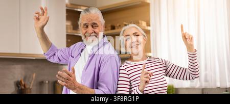 Glückliches älteres kaukasisches Paar tanzt zusammen in der Küche, freudiges Leben Stockfoto