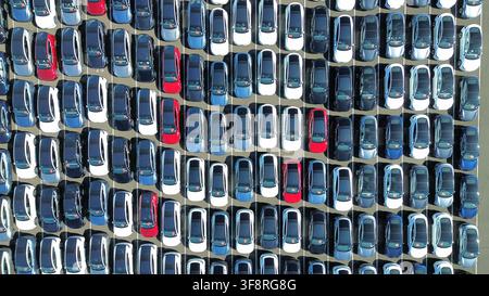Top-Down-Luftbildmuster von neuen Autos, die auf einem großen Fahrzeugverteilplatz geparkt sind Stockfoto