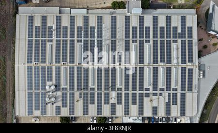 Luftaufnahme einer großen Lagerhallendachfläche, die mit photovoltaischen Solarpanelen bedeckt ist Stockfoto