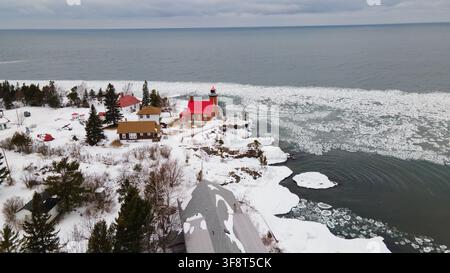 Luftbild des Eagle Harbor Leuchtturms, umgeben von schneebedeckten Gründen und eisigen Gewässern des Lake Superior im Winter in Eagle Harbor, Michigan, Vereinigte Staaten Stockfoto