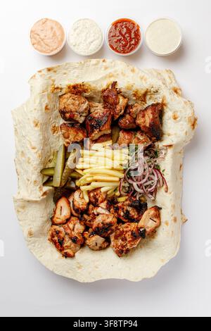 Gemischter gegrillter Fleischteller auf Lavash-Fladenbrot mit Pommes frites und Dips Stockfoto