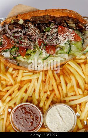 Doner-Kapsalon-Sandwich in Pita-Brot mit Pommes und Soßen Stockfoto