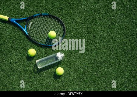 Tennisschläger, Bälle und Wasserflasche auf grünem Rasenplatz arrangiert, Top-Down-Ansicht Sporttraining und Hydrationskonzept mit großzügigem Kopierraum. Stockfoto
