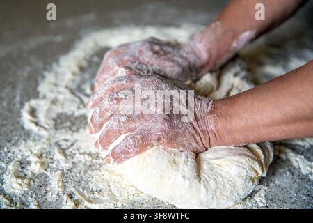 Chef in professioneller Küche bereitet Teig vor. Teigbereitung durch männliche Hände in der Bäckerei. Lebensmittelkonzept. Hände Teig. Weibliche Hände bereiten Teig für Pizza zu Stockfoto