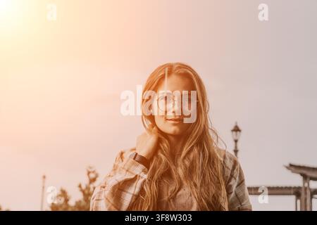 Frauenbrille Sonnenuntergang Porträt einer jungen Frau mit kariertem Hemd und Brille im Freien in der Dämmerung mit Kopierraum Stockfoto