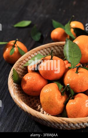 Tangerinen Mandarinenfrucht mit Blättern auf schwarzem Holztisch Stockfoto