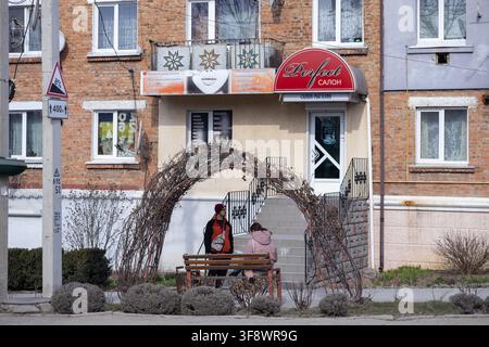 Horodok, Ukraine – 23. März 2026: Die professionelle Salonfassade zeigt klare Beschilderung an einem Backsteingebäude nahe einer Straßenbank, eingerahmt von einem trockenen Pl Stockfoto
