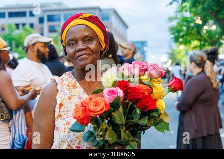 Eine Straßenhändlerin hält einen Blumenstrauß, den sie während Veranstaltungen in Syracuse, NY, verkauft. Stockfoto