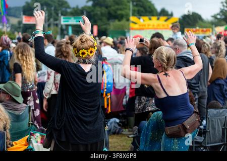 FESTIVALFREUNDE TANZEN MIT ERHOBENEN ÄRMEN, REPORTAGE, GREEN MAN FESTIVAL 2016, BRECON, WALES, UK, 2016: Von hinten gesehen tanzen zwei Frauen mit erhobenen Armen in einer großen Festivalmenge, wobei eine ein schwarzes Oberteil und einen Kranz aus gelben Blumen im Haar trägt. Foto: Rob Watkins. INFO: Das Green Man Festival begann 2003 in Wales. Es findet jährlich an dem dritten Wochenende im August in den Brecon Beacons statt und feiert alternative Musik, Kunst, Literatur, Wissenschaft und familienfreundliche Kultur in einer wunderschönen Berglandschaft. Stockfoto