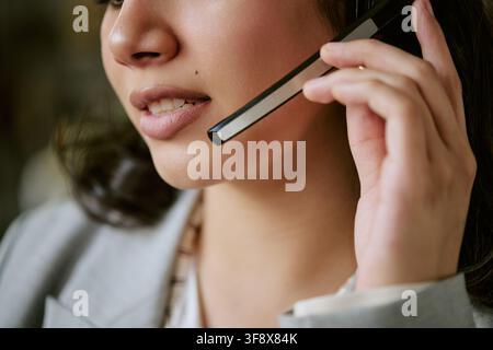 Zuschnitt einer hispanischen Frau, die in ein Headset-Mikrofon spricht Stockfoto
