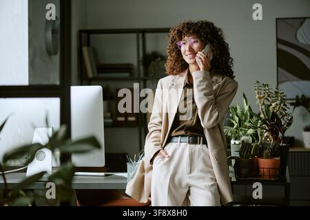 Junge Geschäftsfrau spricht am Smartphone in einem modernen Büro Stockfoto