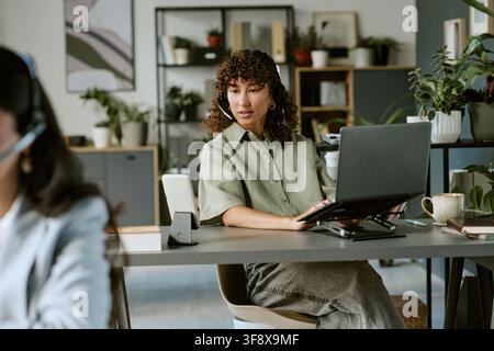 Junge Frau arbeitet an Kundensupport-Aufgaben Stockfoto
