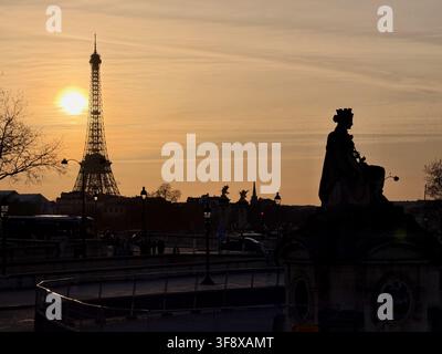 Paris, Frankreich - 26. Februar 2026: Sonnenuntergang über dem Eiffelturm mit Silhouetten der Pont Alexandre III und einer Statue in Paris, Frankreich. Stockfoto